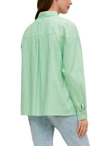 Groen gestreept shirt met lange mouwen, een knoopsluiting kraag en achterplooien. De stof lijkt glad met een lichte textuur.