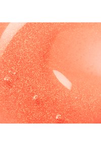 Close-up of glossy, translucent orange gel with small air bubbles and fine shimmering particles suspended inside.