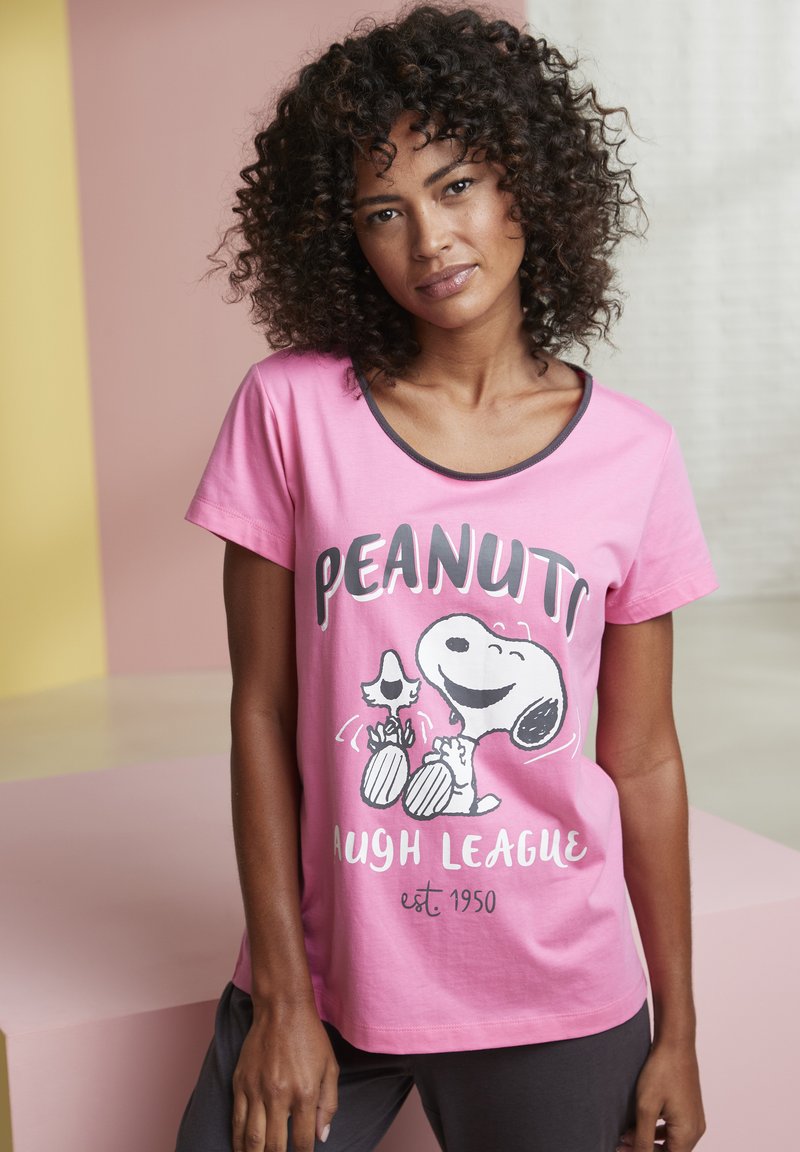 Pink short-sleeve t-shirt featuring a Snoopy graphic with "PEANUTS LAUGH LEAGUE" text, rounded neckline, and relaxed fit.