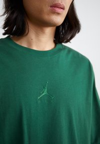 Grøn bomulds t-shirt med en tonal broderet Air Jordan-logo på brystet. Enkel design med rund hals og afslappet pasform.