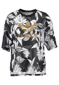 Svart t-shirt med kort ärm som har ett djärvt vitt blommönster, geometriska detaljer och en guldfärgad Adidas-logotyp med leopardtryck framtill.