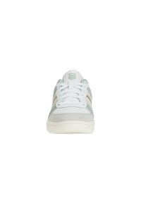 Athletic shoes featuring a white leather upper with mint green and cream suede accents, round toe, and white laces. K-Swiss logo on tongue.