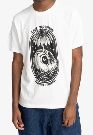 T-shirt blanc avec un graphisme noir d'un crâne d'où pousse une fleur, sous le texte "Late Bloomers" et "Element & Timber!" à l'avant.