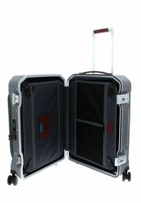 Valigia rigida con esterno grigio, struttura in alluminio, doppie ruote e maniglia retrattile. L'interno presenta compartimenti e tasche in tessuto scuro.