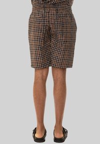 Pantaloni corti marroni con un design a pois in tonalità marrone scuro e più chiare, dotati di una cintura elastica e tasche laterali.