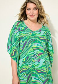 Grön mönstrad kaftan med flytande design, med vågiga ränder i nyanser av grönt, lila och ljusblått. Lättviktig tyg, vida ärmar.