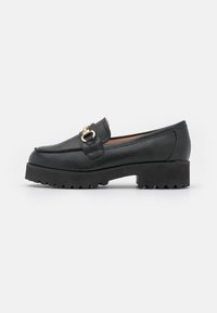 Mocassino nero con suola in gomma spessa e hardware in tono dorato. Caratterizzato da dettagli cuciti e una texture in pelle liscia. Design casual e moderno.