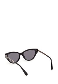 Gafas de sol de forma cat-eye en color negro, con un marco de plástico brillante, lentes oscuros y acentos en tono dorado en las patillas. Forma elegante y angular.