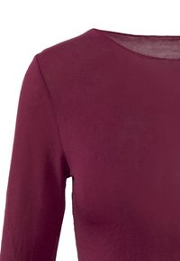 Top bordeaux a maniche lunghe realizzato in tessuto morbido e elastico, con scollatura rotonda e dettagli di cucitura minimali.