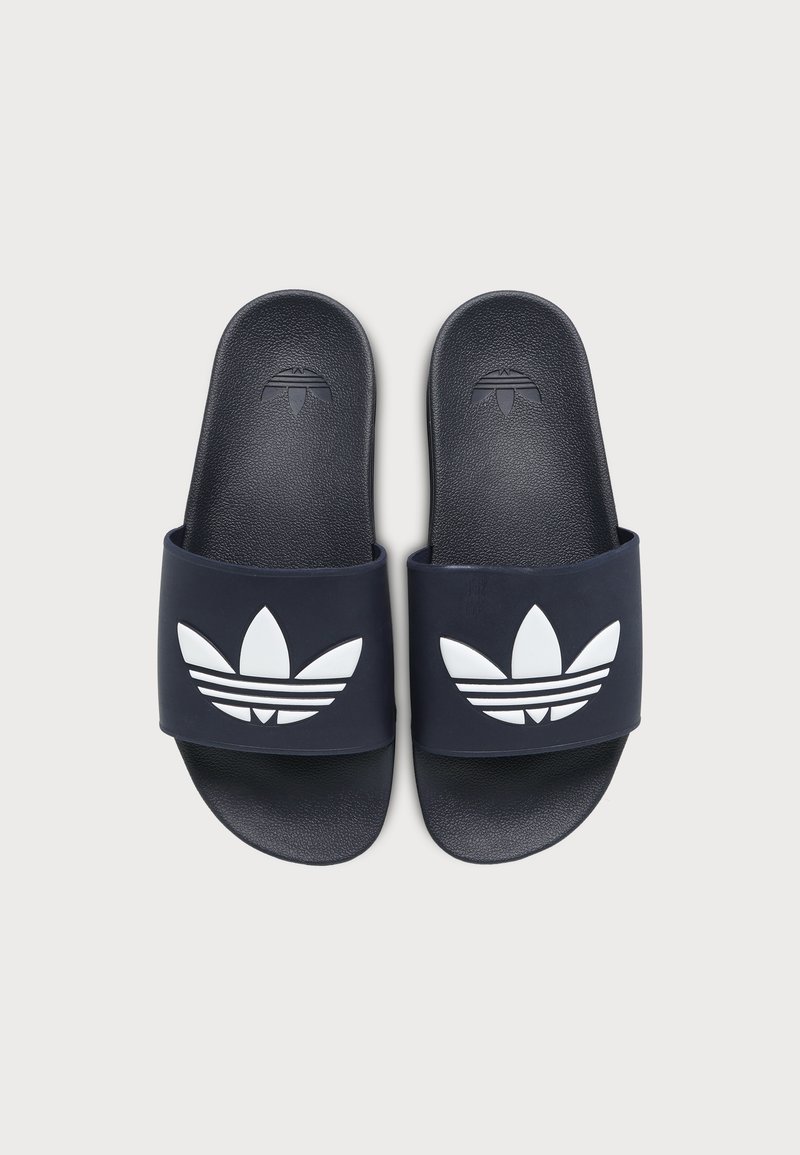 Paar schwarze Slide-Sandalen mit weißem Adidas Trefoil-Logo auf den Riemen, von oben auf hellem Hintergrund gezeigt.