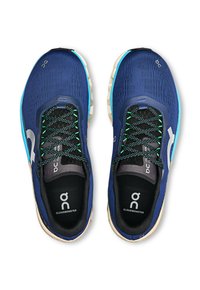Blue athletic shoes with mesh upper, black laces, green accents, and logo on sides. Thick cushioned sole enhances comfort and support.