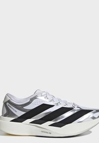 Λευκό και ασημί αθλητικό παπούτσι Adidas με μαύρες ρίγες και χοντρή λευκή σόλα με την ένδειξη "Lightstrike Pro" σε απλό φόντο.