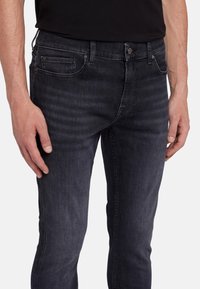 Jeans in denim blu scuro con una vestibilità slim, dotati di tasche frontali, chiusura con bottone e leggere sfumature in tutto il tessuto.