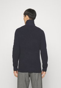 Marineblau gestrickter Pullover mit hohem Kragen, geripptem Muster, langen Ärmeln und lockerer Passform. Klassisches Design, geeignet zum Layering.