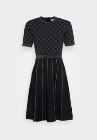 Robe en maille noire à manches courtes, avec un motif losange blanc. Jupe évasée à rayures verticales et col rond.