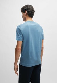 T-shirt azzurro chiaro a maniche corte, colletto rotondo, morbido tessuto di cotone, vestibilità regolare, design minimalista, piccolo logo dettagliato sull'orlo.