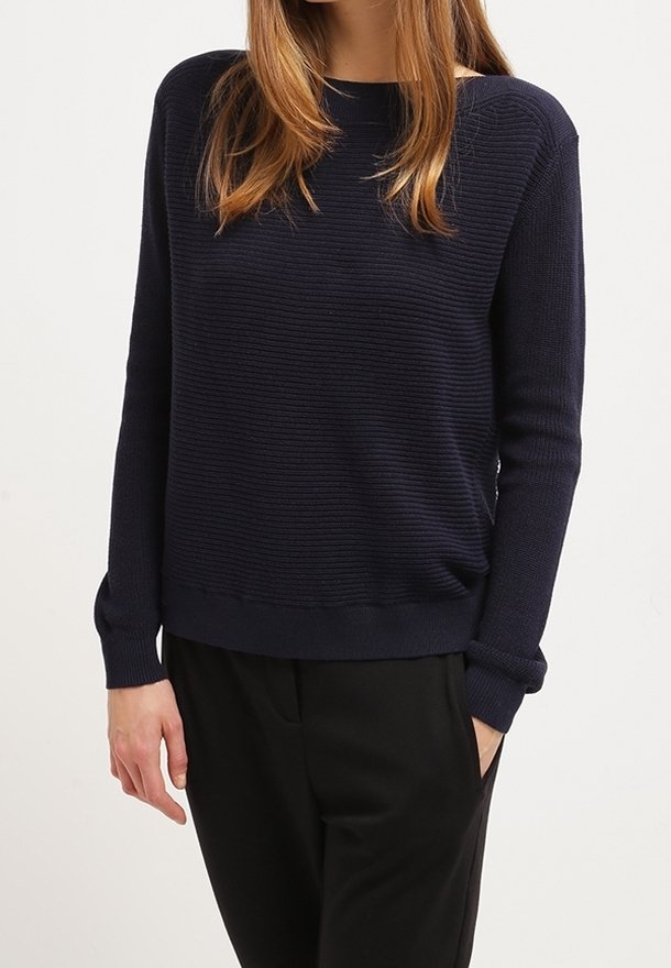 Pull en maille bleu marine avec une texture côtelée, col arrondi et manches longues ; associé à un pantalon noir sur mesure.