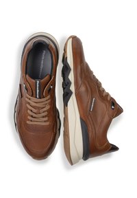 Chaussures en cuir marron avec un laçage, surface texturée, semelle en caoutchouc noir contrastant et marque discrète sur le côté.