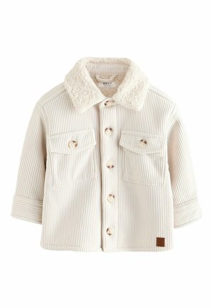 Cremfarbene Cordjacke mit einem Kunstfellkragen, zwei Brusttaschen, Holzknöpfen und aufgeschlagenen Ärmeln. Strukturierte Stoffdetails sind sichtbar.