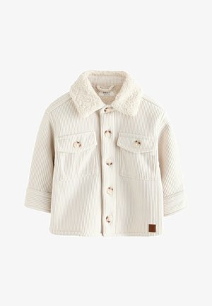 Giacca camicia in corduroy crema con colletto in finta pelliccia, due tasche sul petto, bottoni in legno e maniche arrotolate. Dettaglio del tessuto testurizzato visibile.