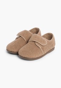 Pantuflas de felpa color marrón claro con una correa de gancho y bucle y puntas redondeadas, que presentan una textura suave y suelas planas de color marrón. Diseño simple, sin patrones.