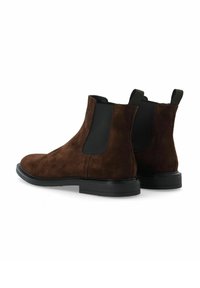 Botas de ante marrón hasta el tobillo con paneles laterales elásticos, punta redonda y suelas de goma negra. Presentan un tirador en cada talón para facilitar su uso.