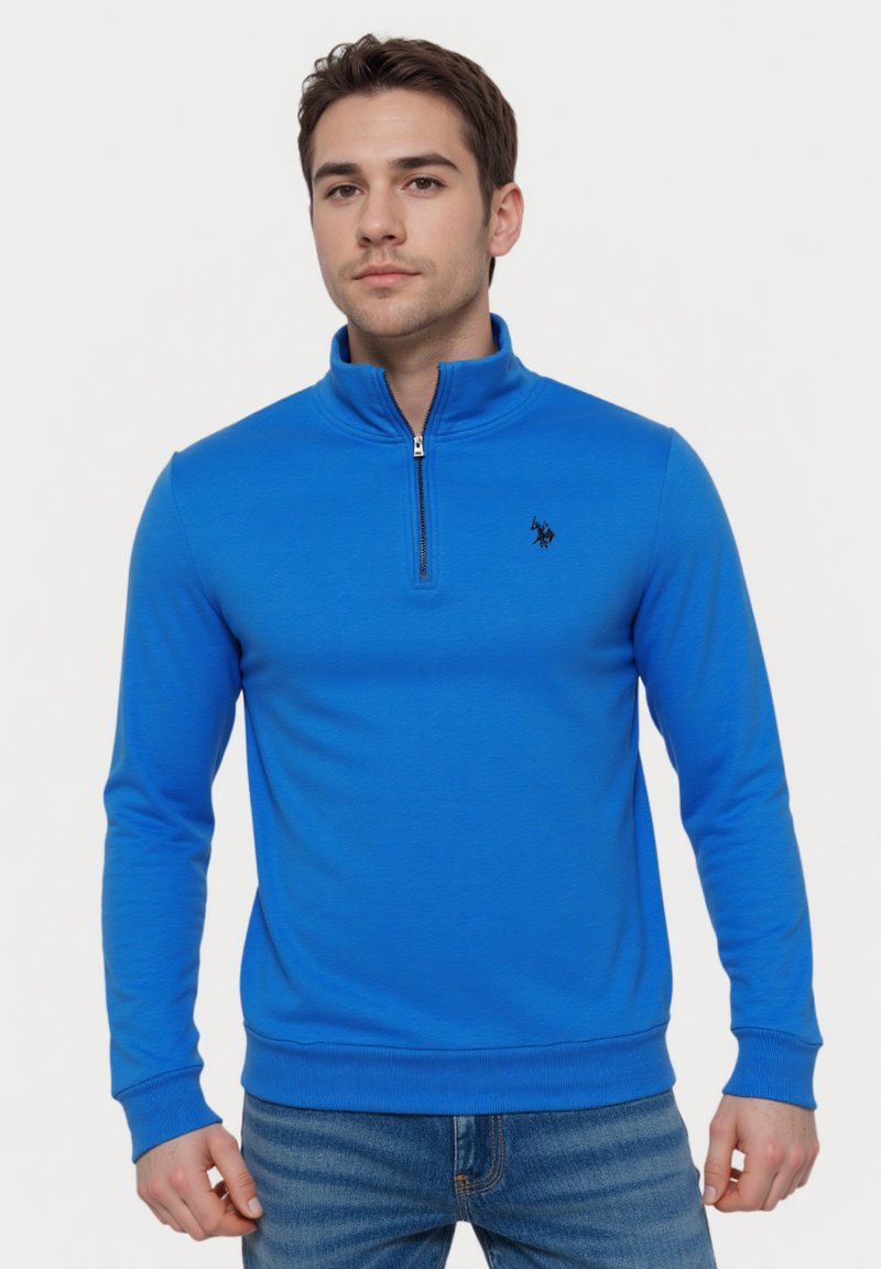 Blauwe pullover sweatshirt met hoge kraag, rits en geribde manchetten. Voorzien van een klein zwart logo op de borst. Zachte stof, aansluitend ontwerp.