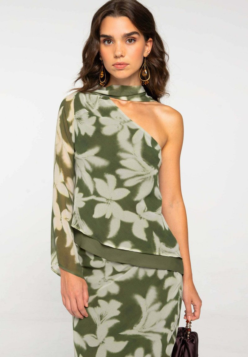 Top verde con estampado floral, diseño de un solo hombro, material ligero y manga caída. Presenta una textura suave y una silueta fluida.