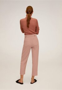 Top de manga larga de color rosa con textura acanalada, combinado con pantalones tailored de color rosa claro, con cintura alta y dos bolsillos traseros, llevado con sandalias negras.