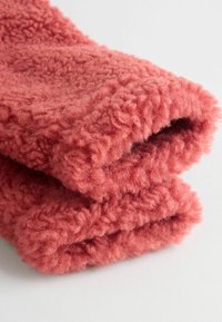 Teksturowana, zwinięta frotte w miękkim koralowym kolorze, z puszystą, pętelkową powierzchnią i grubą, ciepłą konstrukcją.