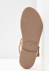 Sandal in pelle color tan con cinturino regolabile, suola in gomma testurizzata e logo del brand inciso. Taglia 38 indicata sulla suola.