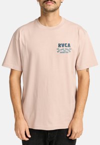 Pink bomulds t-shirt med korte ærmer og rund halsudskæring, med blå grafisk tekst på det øverste venstre brystområde.
