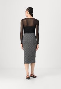 Haut à manches longues en maille noire associé à une jupe midi ajustée à motifs géométriques noir et blanc. Présente une silhouette élancée et des détails subtils.