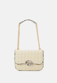 Kviiltattu beige käsilaukku, jossa on kulta ketjuolkaimia. Siinä on käärmeennahkakuosiset yksityiskohdat ja pyöreä lukko, jossa on brändin nimi kohokuvioituna.