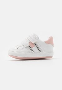 Białe sneakersy z różowymi akcentami, wykonane z materiału syntetycznego, o zaokrąglonym kształcie, z rzepem, z perforowanymi detalami na palcach oraz gumową podeszwą.