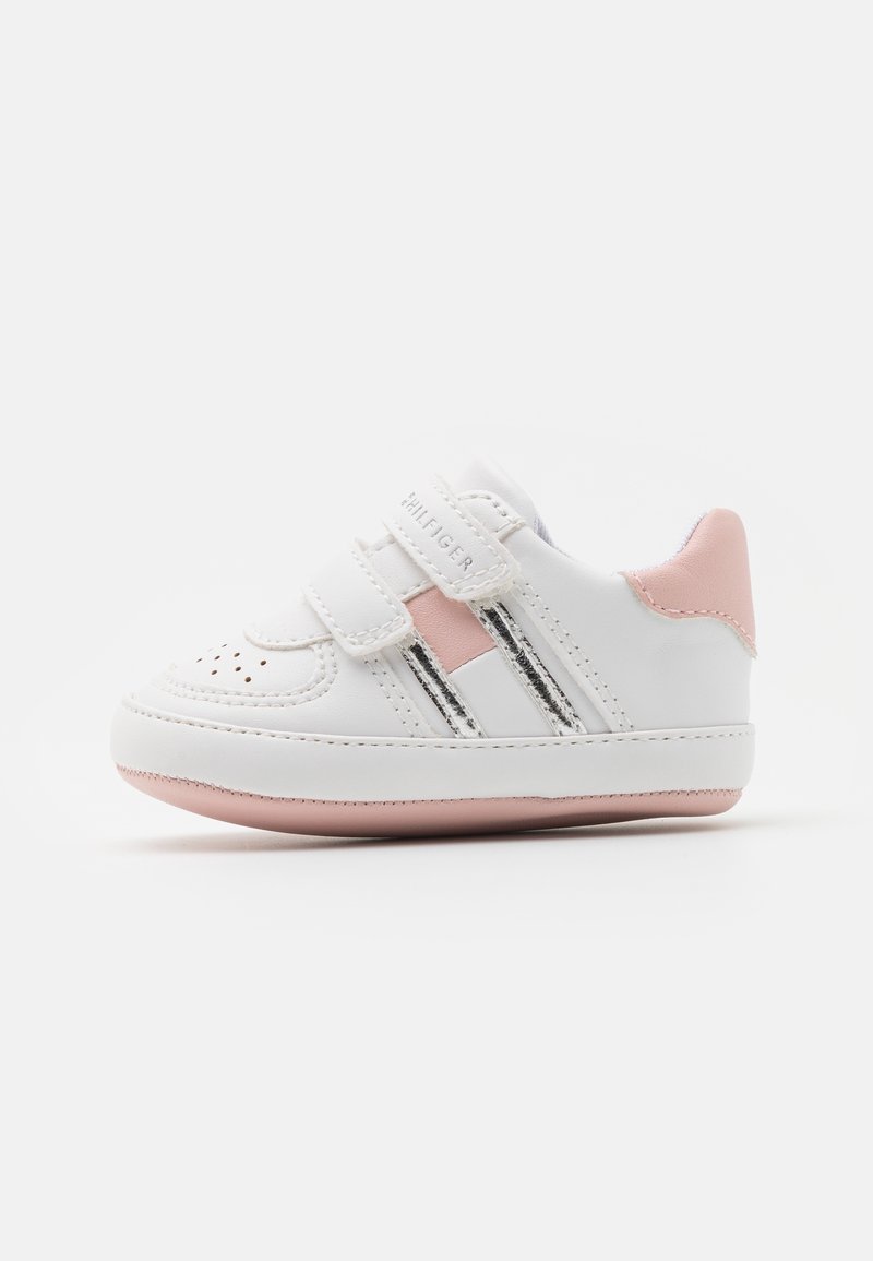 Białe sneakersy z różowymi akcentami, wykonane z materiału syntetycznego, o zaokrąglonym kształcie, z rzepem, z perforowanymi detalami na palcach oraz gumową podeszwą.