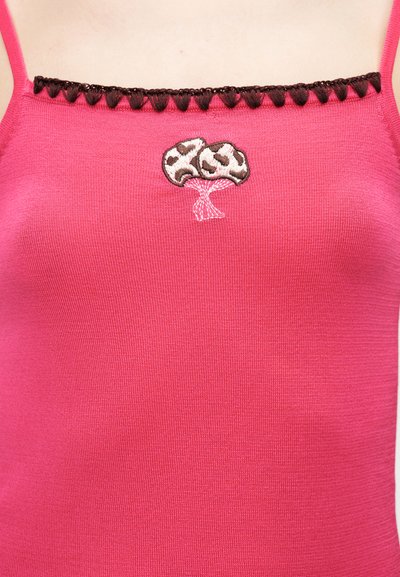 Ροζ αμάνικη μπλούζα με λεπτές τιράντες, καφέ περιθώριο κατά μήκος του ντεκολτέ και κεντητό σχέδιο δέντρου σε καφέ και λευκό στο κέντρο του στήθους.