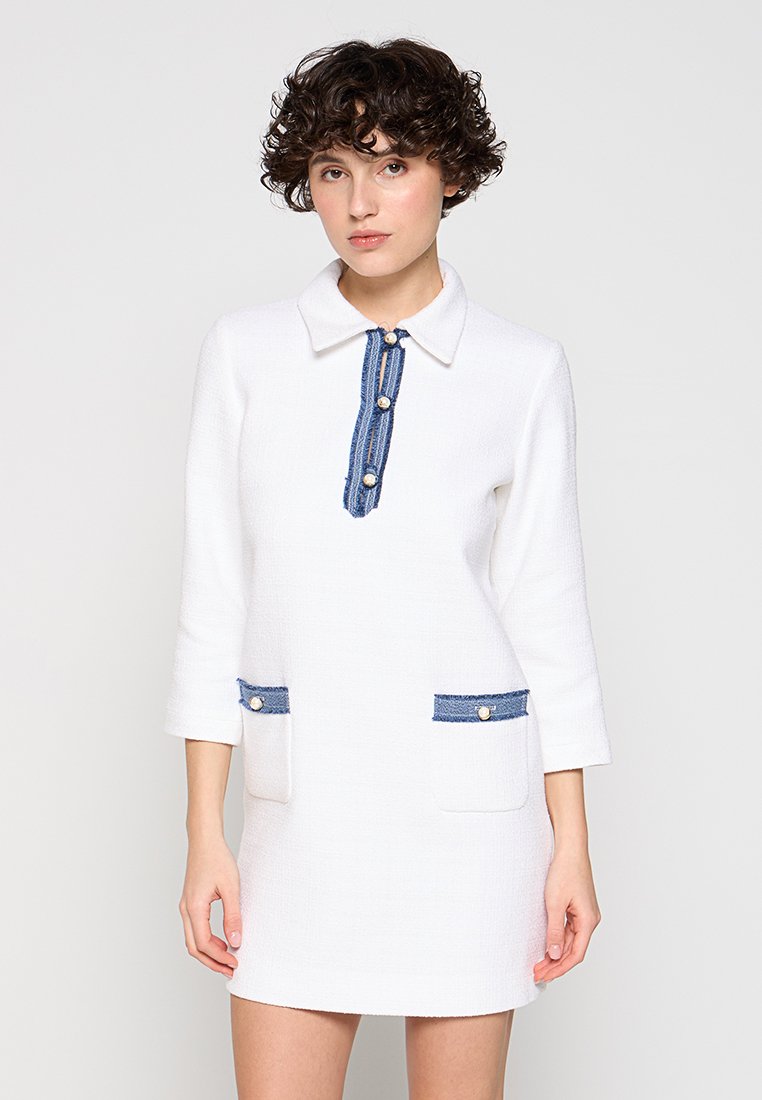 Weißes Kleid mit kragenförmigem Ausschnitt, blauen Denim-Akzenten an den Taschen und der Knopfleiste, dreiviertel Ärmel, strukturiertes Gewebe.
