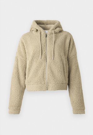 Felpa beige tagliata, realizzata in tessuto testurizzato e morbido. Presenta una zip frontale, cappuccio con cordino e maniche a vestibilità rilassata.