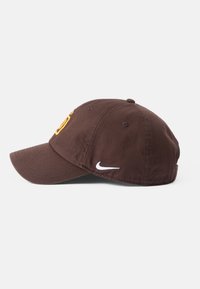 Brązowa czapka baseballowa z wygięnym daszkiem, z żółtym logotypem z przodu i białym logo Nike z boku; materiał bawełniany.