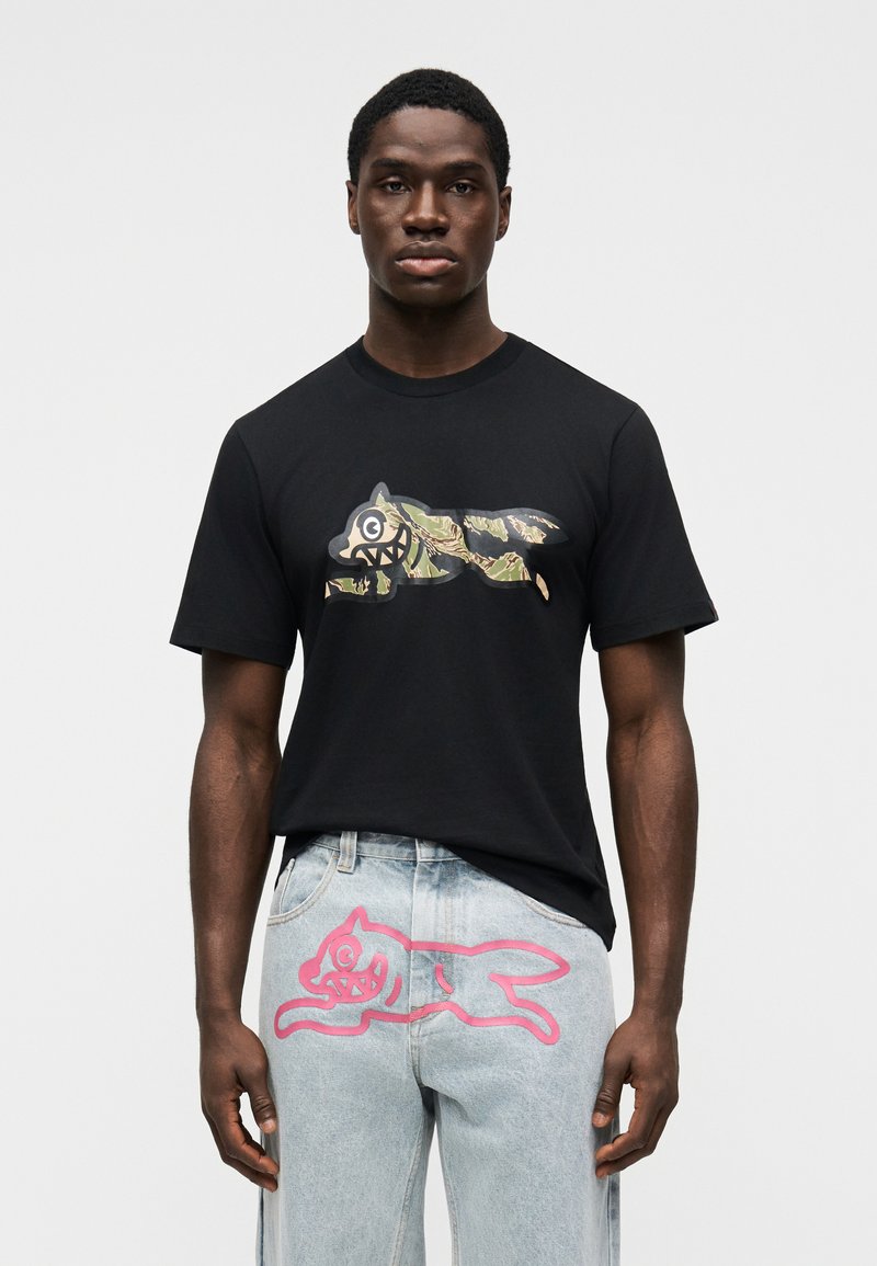 Μαύρο βαμβακερό μπλουζάκι με παραλλαγής γραφικό ενός λύκου. Ανοιχτό μπλε τζιν με ροζ ζωγραφιά ζώου  στη πίσω τσέπη.