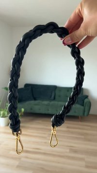 Μαύρη πλεξούδα από δέρμα με χρυσά κλιπ στα δύο άκρα. Λείος υφής και στρογγυλό σχήμα, κατάλληλη για τσάντες ή αξεσουάρ.
