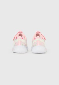 Baskets pour enfants en blanc et couleurs pastel, avec un design ondulé, des pois et une languette en tissu au talon pour un enfilage facile.
