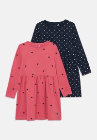Due vestiti a maniche lunghe: uno rosa con motivi a cuore neri, l'altro blu navy con pois dorati. Entrambi presentano un design con gonna arricciata.