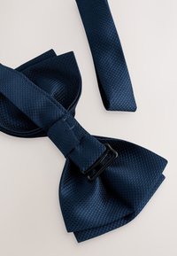 Papillon blu navy in tessuto strutturato, caratterizzato da un nodo con fibbia nera e due lunghe fascette che si estendono dal papillon.