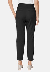 Zwarte broek met een gladde textuur, verkorte lengte en opgerolde mouwen. Voorzien van twee achterzakken en een tailleband met riemlussen.