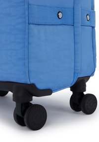 Soft-sided blue suitcase with textured fabric, black plastic wheels, and reinforced corners. Features a side handle and stitched accents.