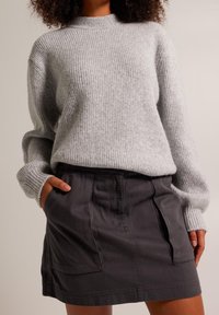 Ljusgrå ribbad tröja med hög krage, matchad med en mörkgrå kjol som har två frampocketar och en avslappnad passform.