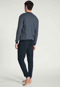 Langsleeve marineblauw gestreept shirt gecombineerd met effen donkere broek, beide van zacht materiaal; relaxte pasvorm met geribde manchetten en tailleband.