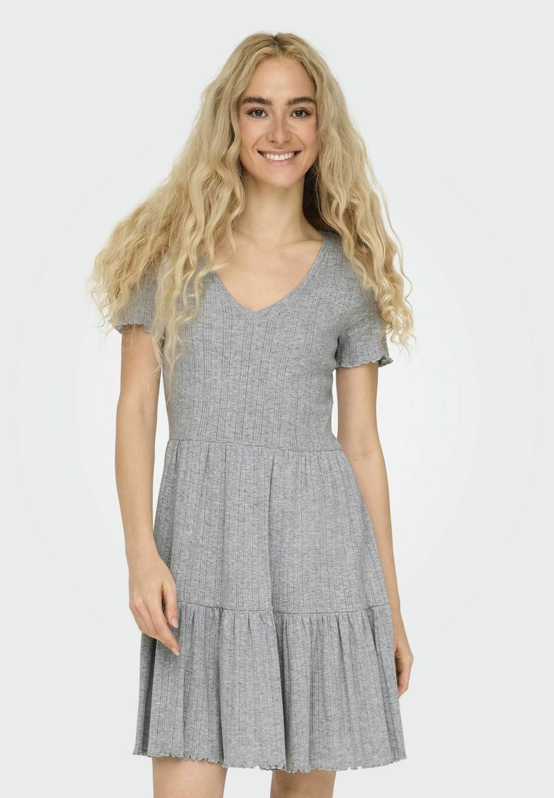 Grå klänning med kort ärm och V-ringning, texturerad tyg, åtsittande bodice och utsvängd, veckad kjol. Utsmyckning med scalloped fåll i botten.